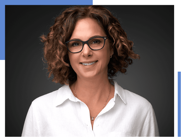 Smiling woman with curly hair and glasses.